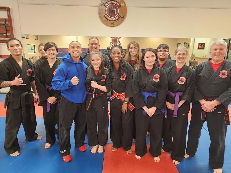 A group of people in karate uniforms are posing for a picture in a gym.