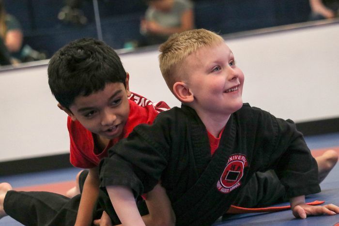 Two young boys are laying on the floor in a gym.