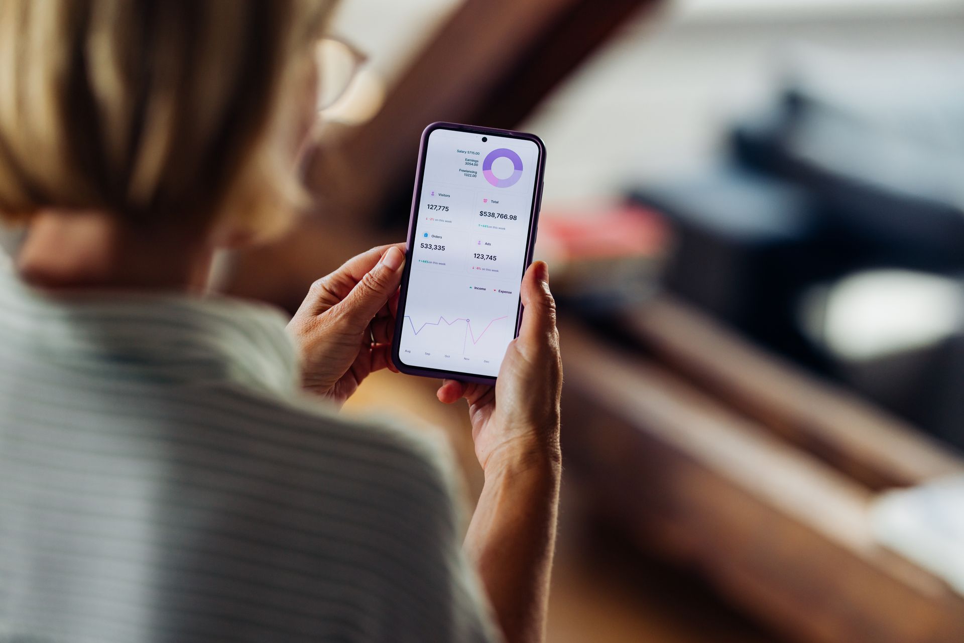 Person holding a phone, looking at a health app with charts and data.
