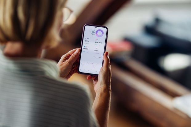 Person holding a phone, looking at a health app with charts and data.