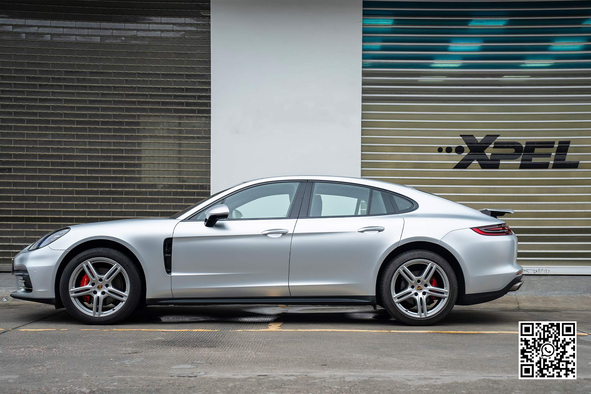 una porsche panamera argento è parcheggiata davanti a un garage .