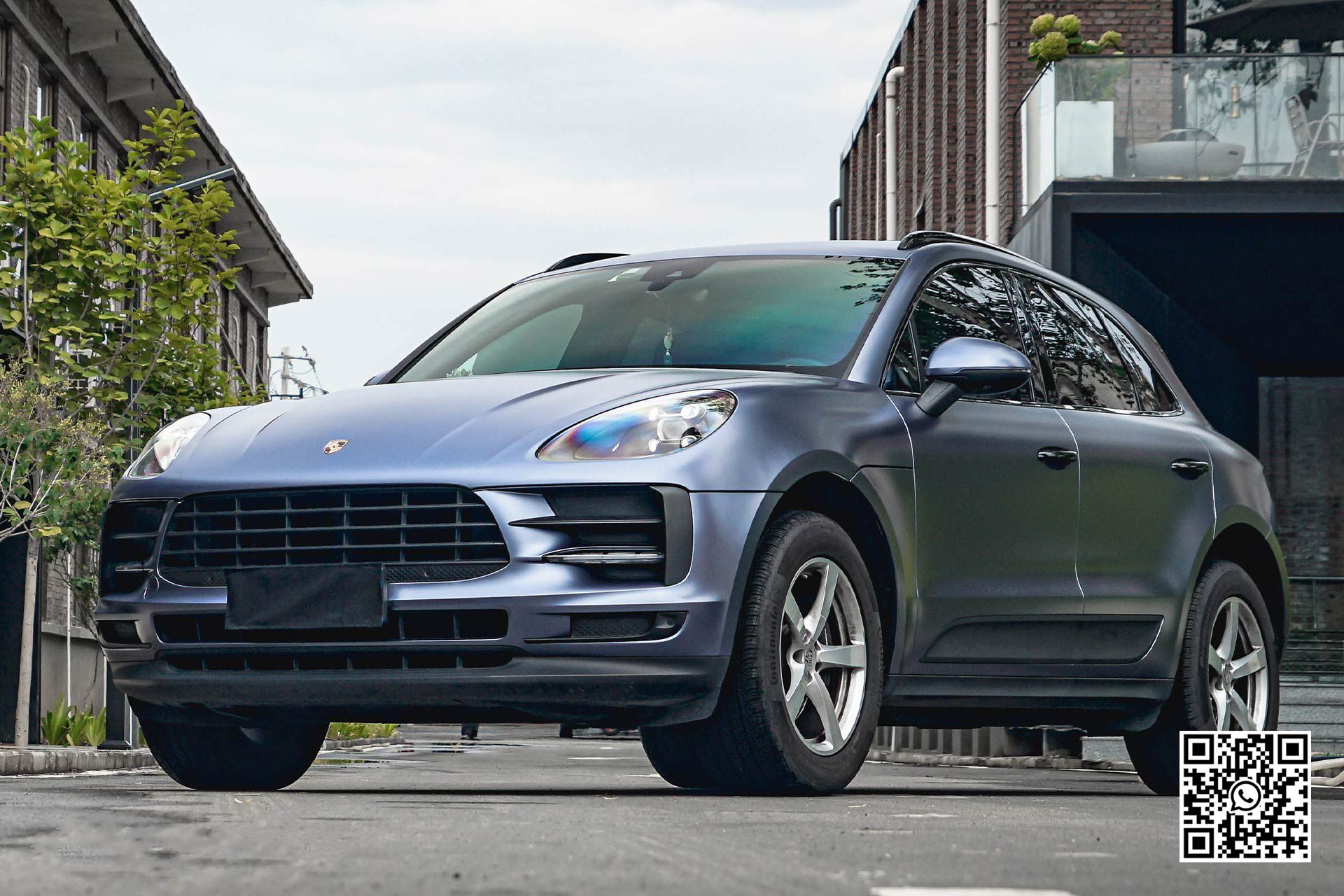 una porsche macan è parcheggiata in un parcheggio accanto a un edificio .