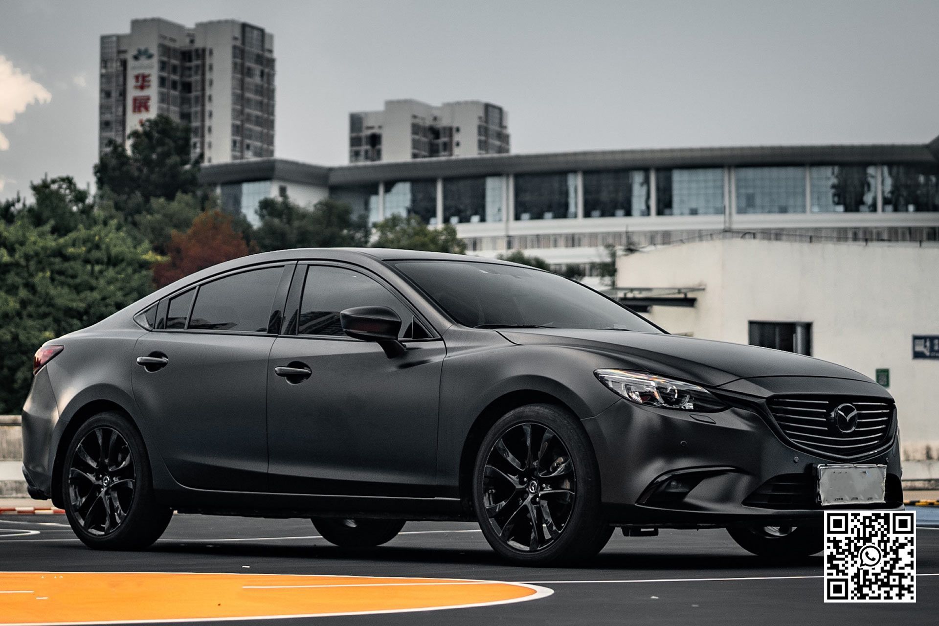 un'auto nera è parcheggiata in un parcheggio davanti a un edificio .