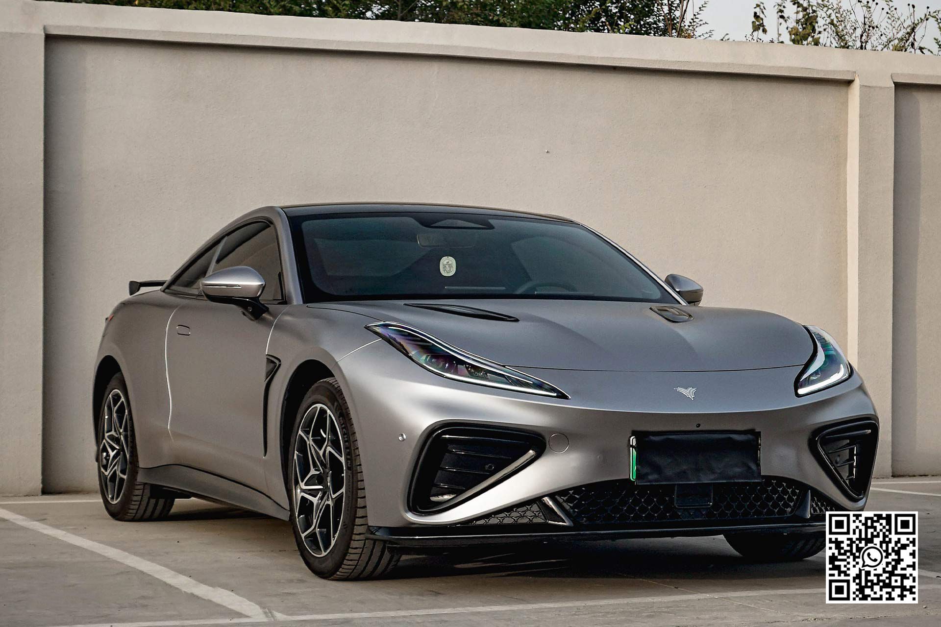 una sportiva grigia è parcheggiata davanti a un muro .