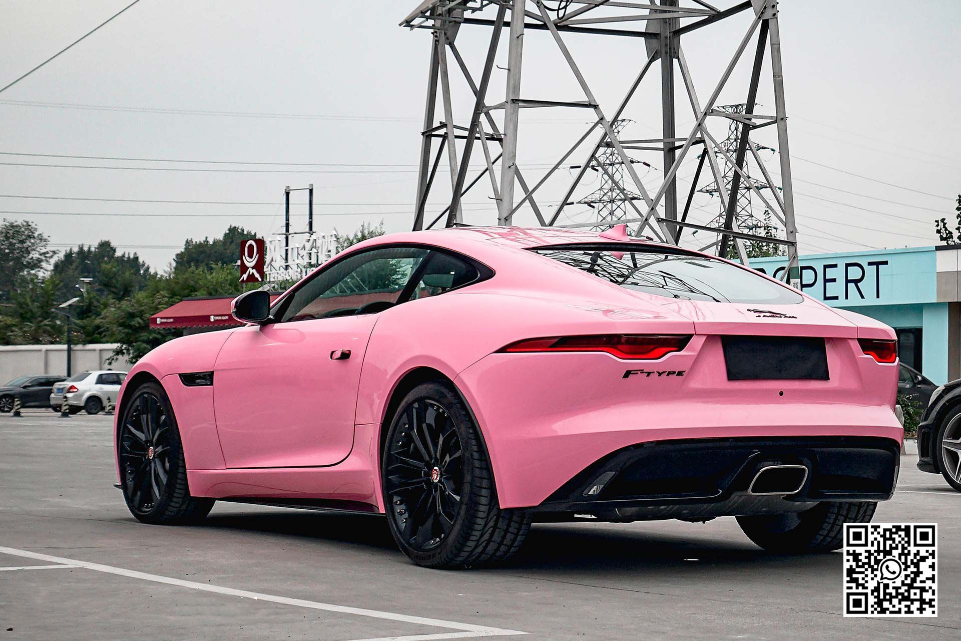una jaguar f type rosa è parcheggiata in un parcheggio .