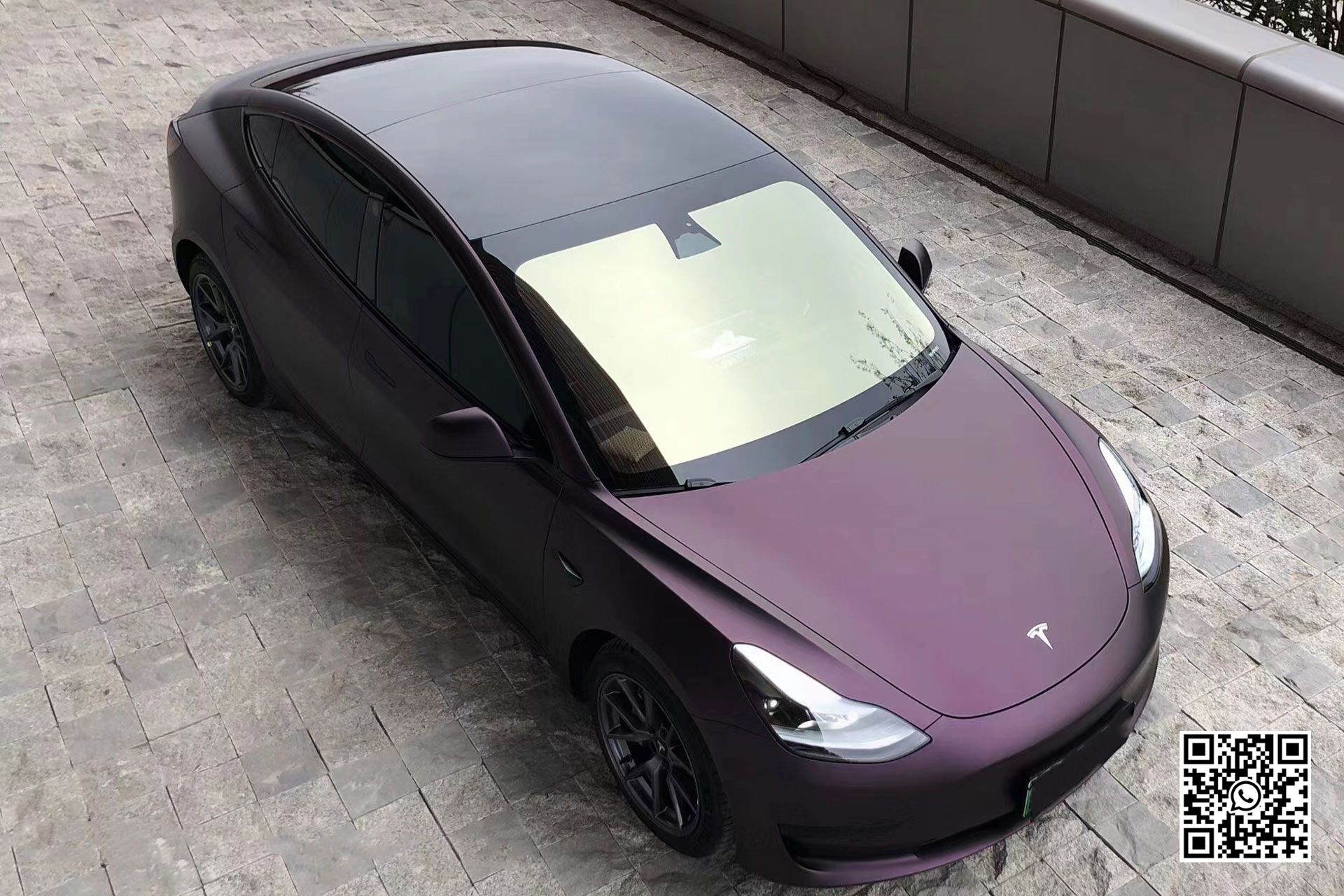 una tesla model 3 viola è parcheggiata in un parcheggio .