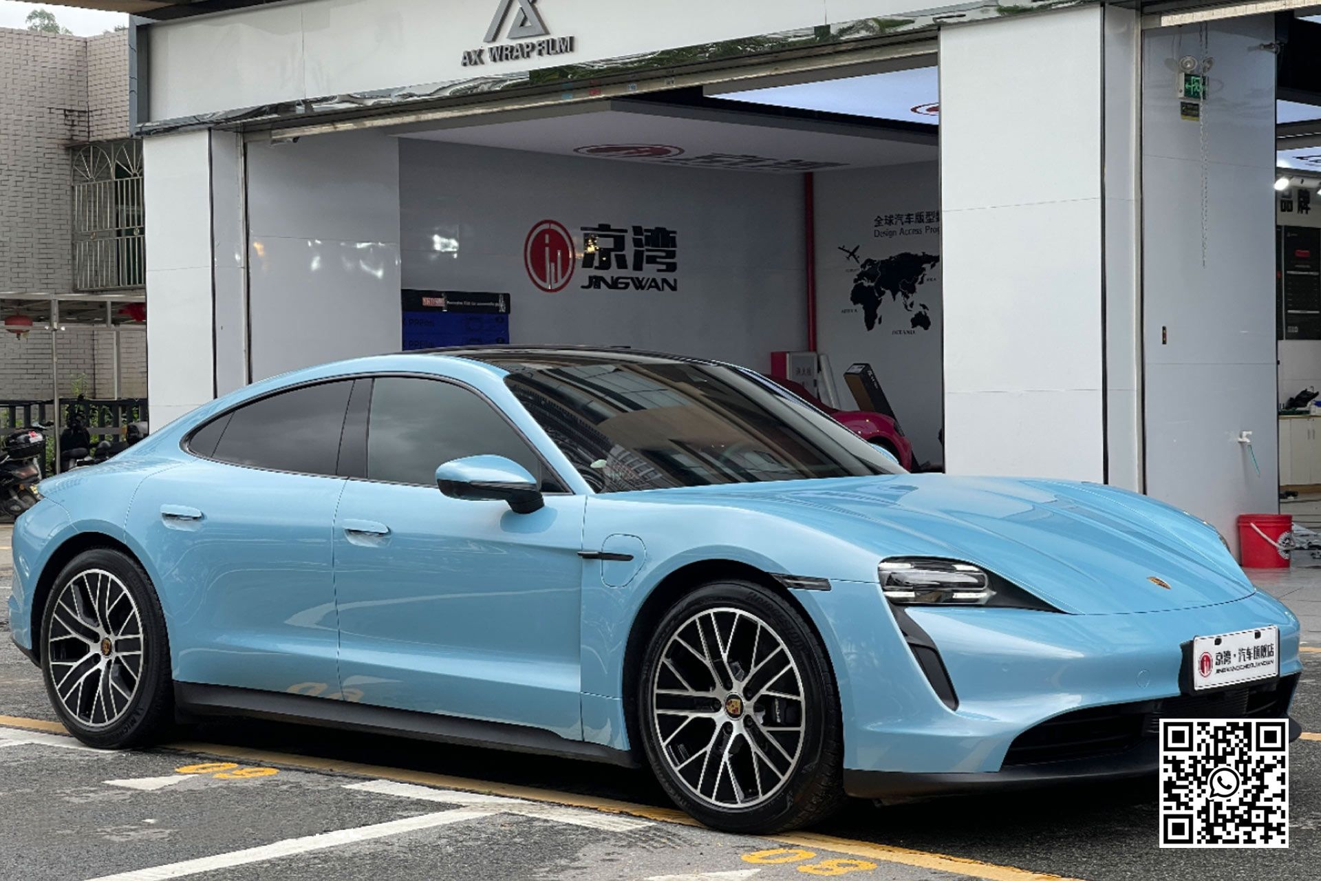 una porsche taycan blu è parcheggiata davanti a un garage .