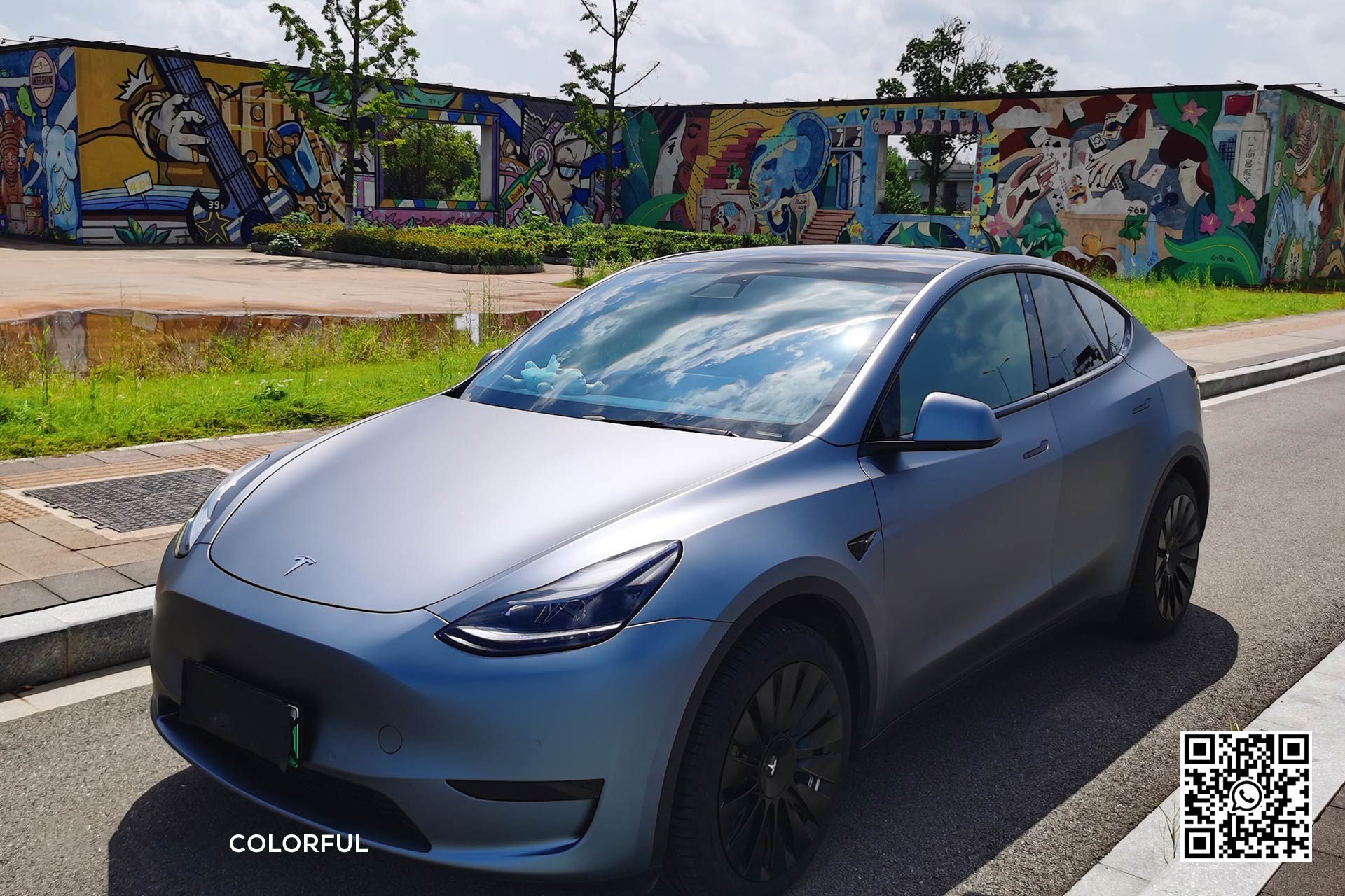 una tesla model y è parcheggiata sulla strada davanti a un muro di graffiti .