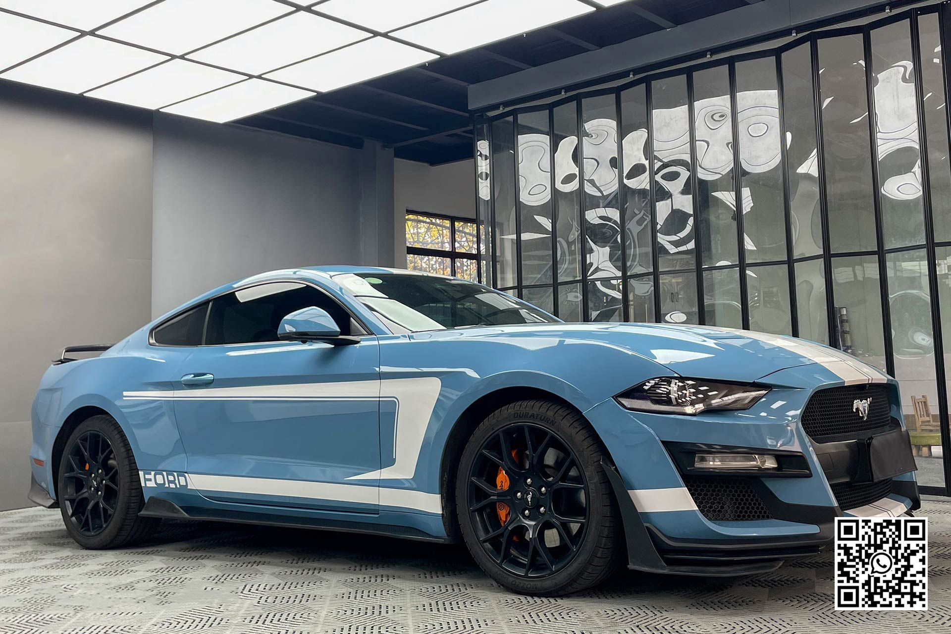 una mustang blu e bianca è parcheggiata in un garage .