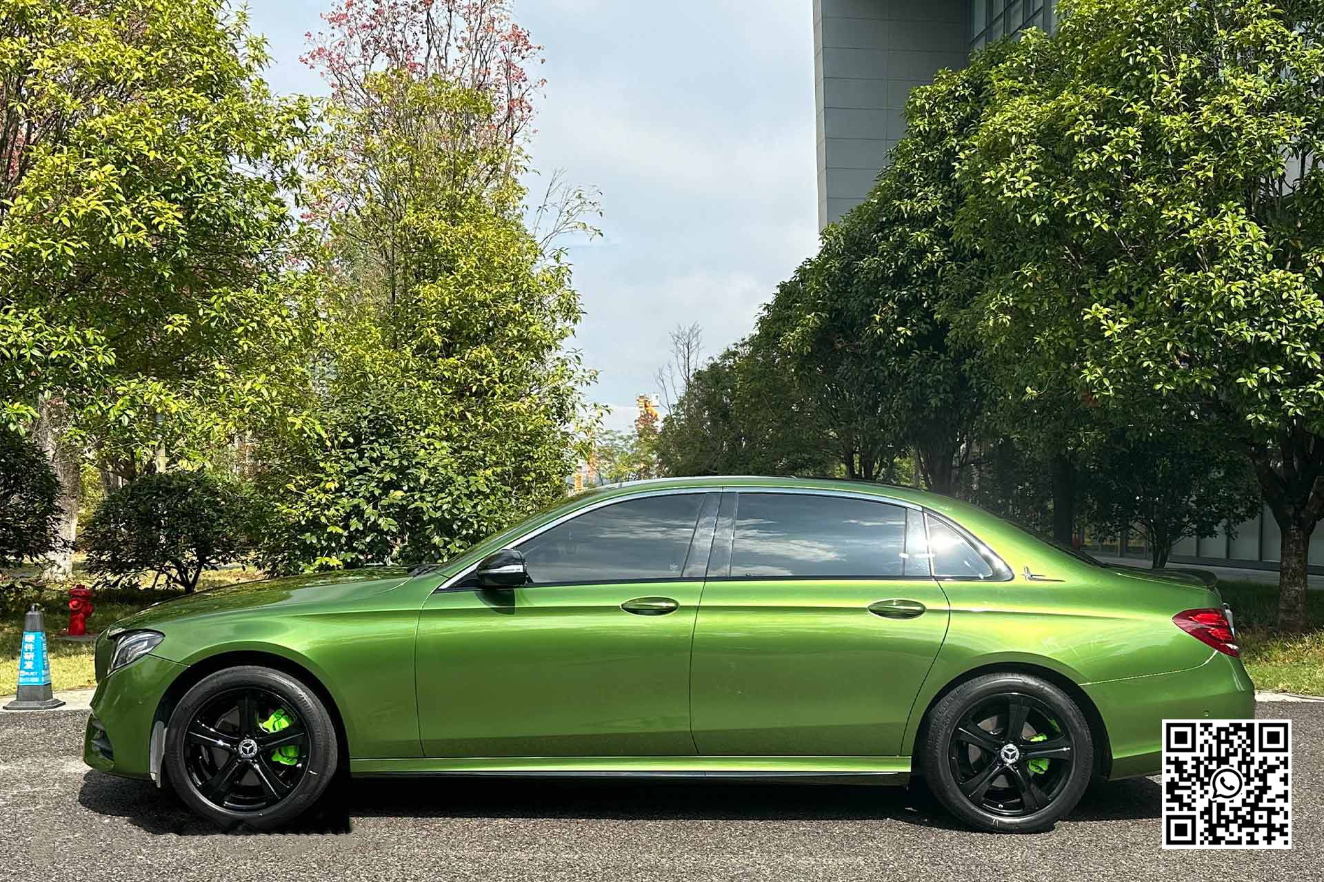 un'auto verde è parcheggiata in un parcheggio circondato da alberi .