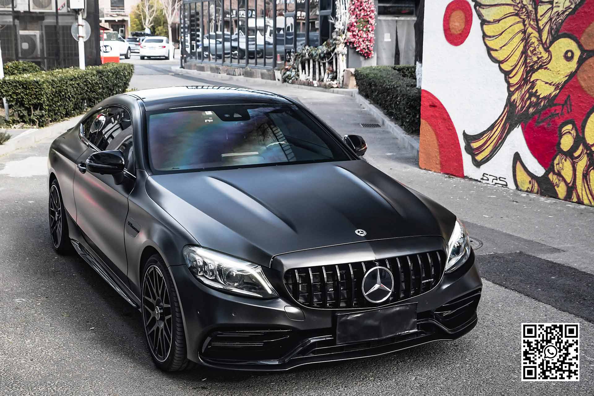 una mercedes benz è parcheggiata davanti a un muro di graffiti .