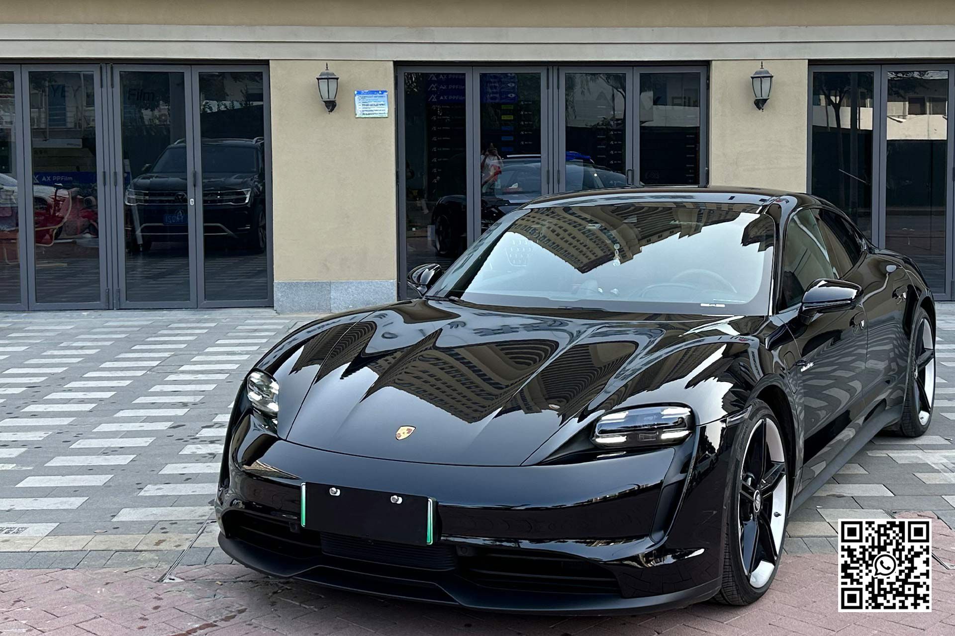 una porsche taycan nera è parcheggiata davanti a un edificio .