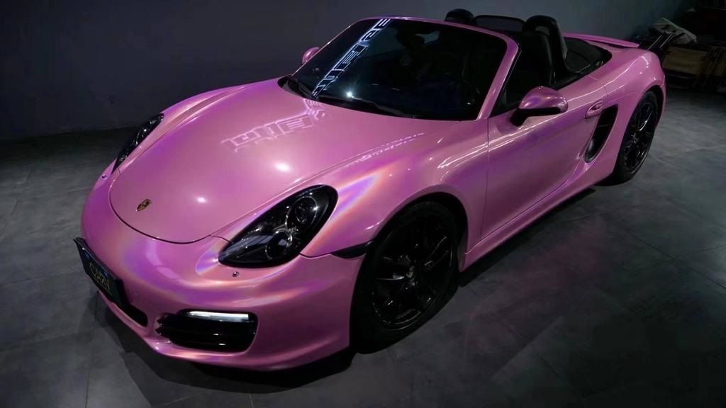 una porsche boxster rosa è seduta su un pavimento .