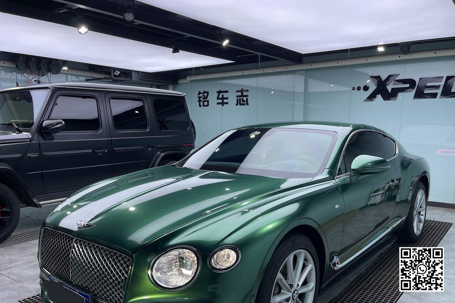 una bentley continental gt è parcheggiata in un garage accanto a un suv nero .