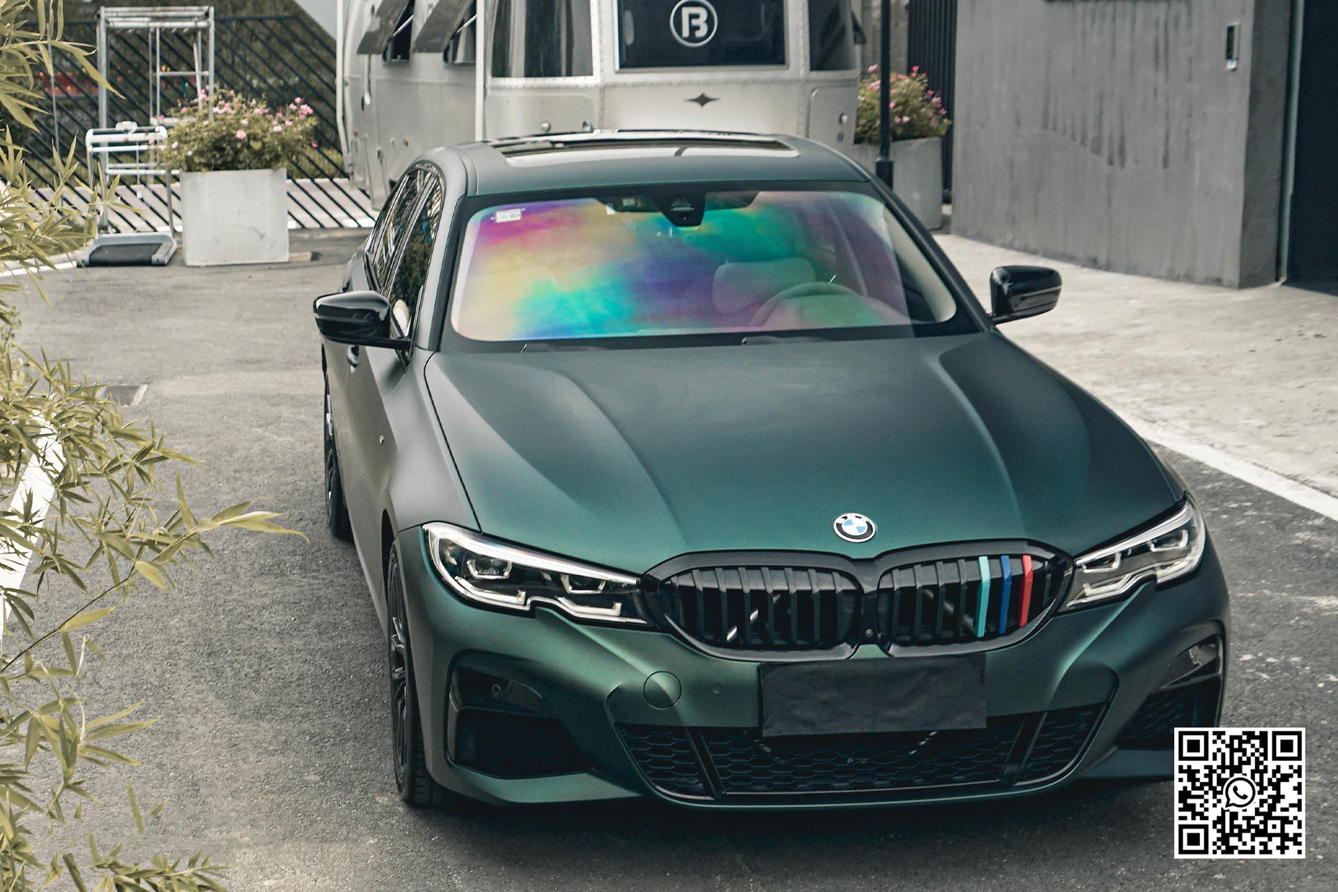 una bmw verde è parcheggiata davanti a un edificio .