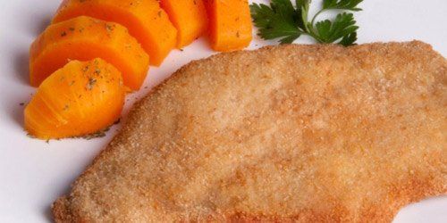 Un primer plano de una pechuga de pollo empanizada en un plato con zanahorias.