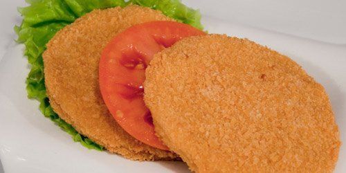 Dos hamburguesas de pollo con tomate y lechuga en un plato blanco.