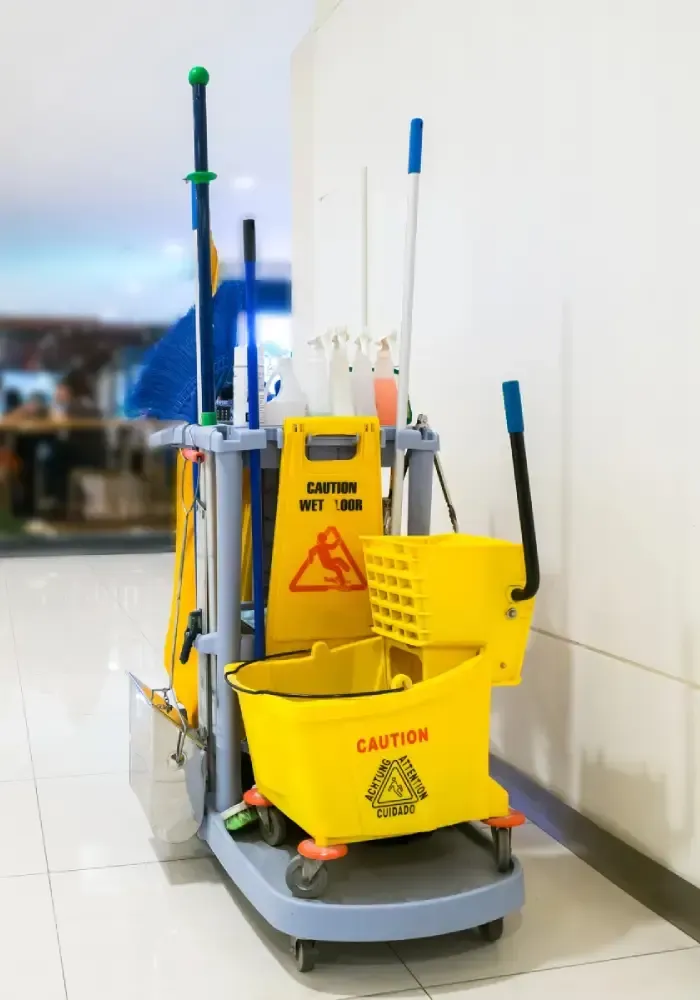 Commercial janitorial cart with mop, caution signs, and cleaning supplies.