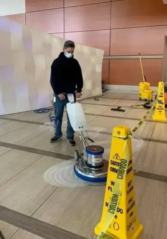 Cleaner using floor buffer during commercial cleaning in Bridgeport lobby.