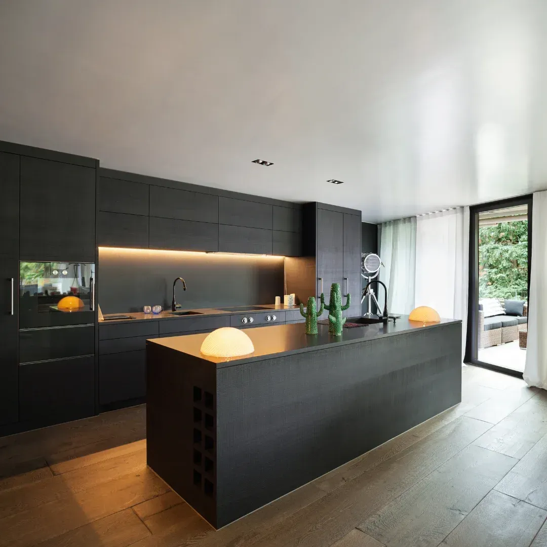 A kitchen with black cabinets and a large island in the middle.