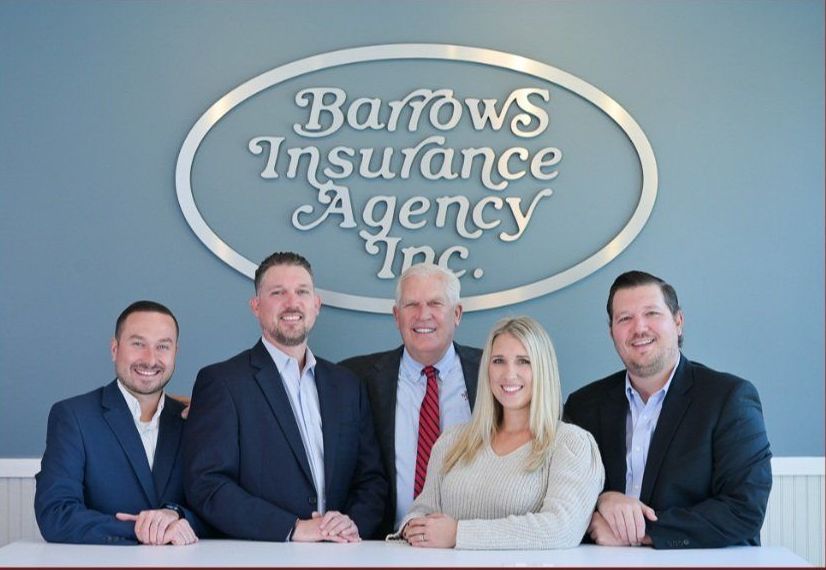 A man is pointing at a laptop while another man looks on