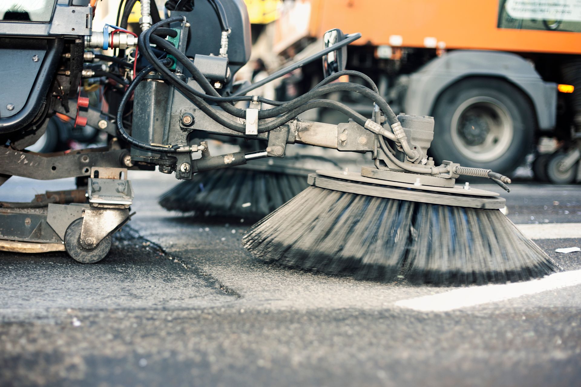 Close-up of industrial brushes used by street sweeping contractors to clean urban roads.