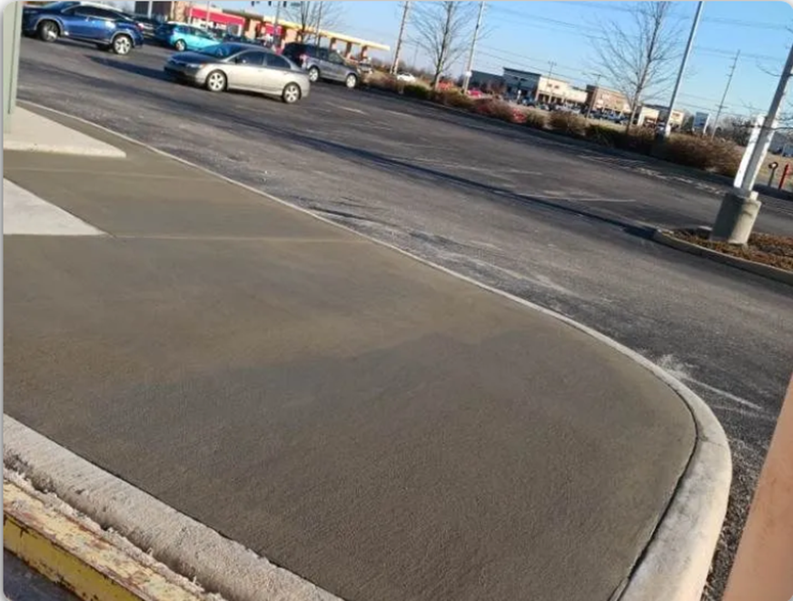 Freshly poured concrete sidewalk beside parking lot with smooth finish at commercial area site. Freshly poured concrete sidewalk beside parking lot with smooth finish at commercial area site.