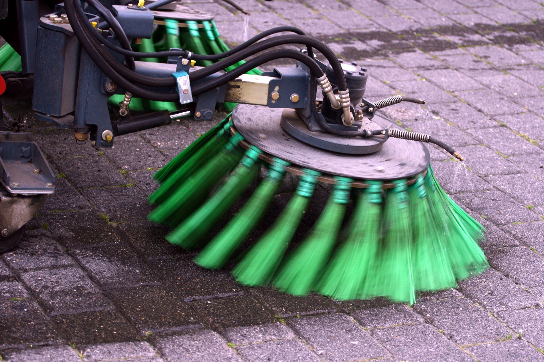 Street sweeper brushes cleaning a paved surface.