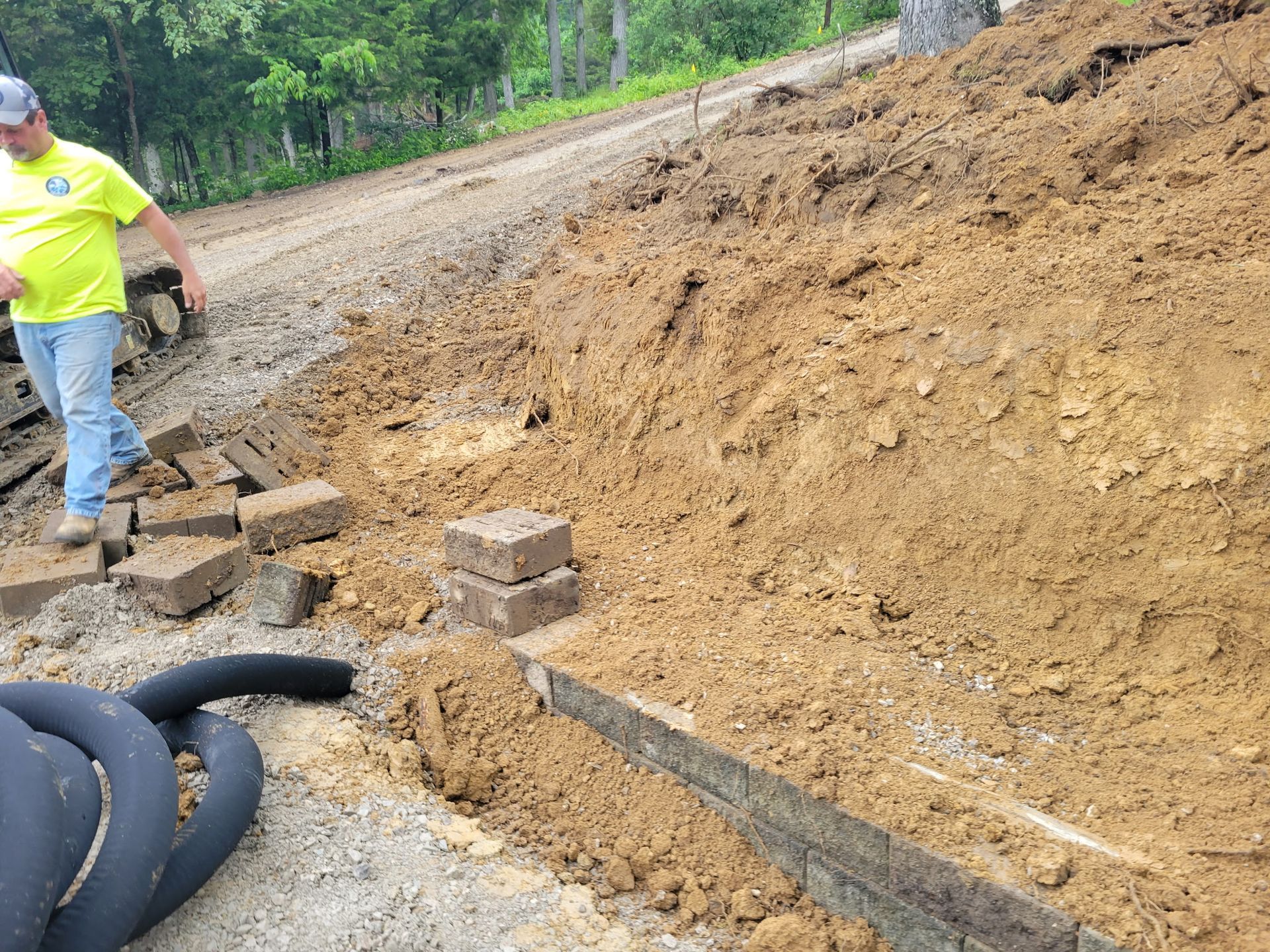 A man in a yellow shirt is standing next to a pile of dirt.