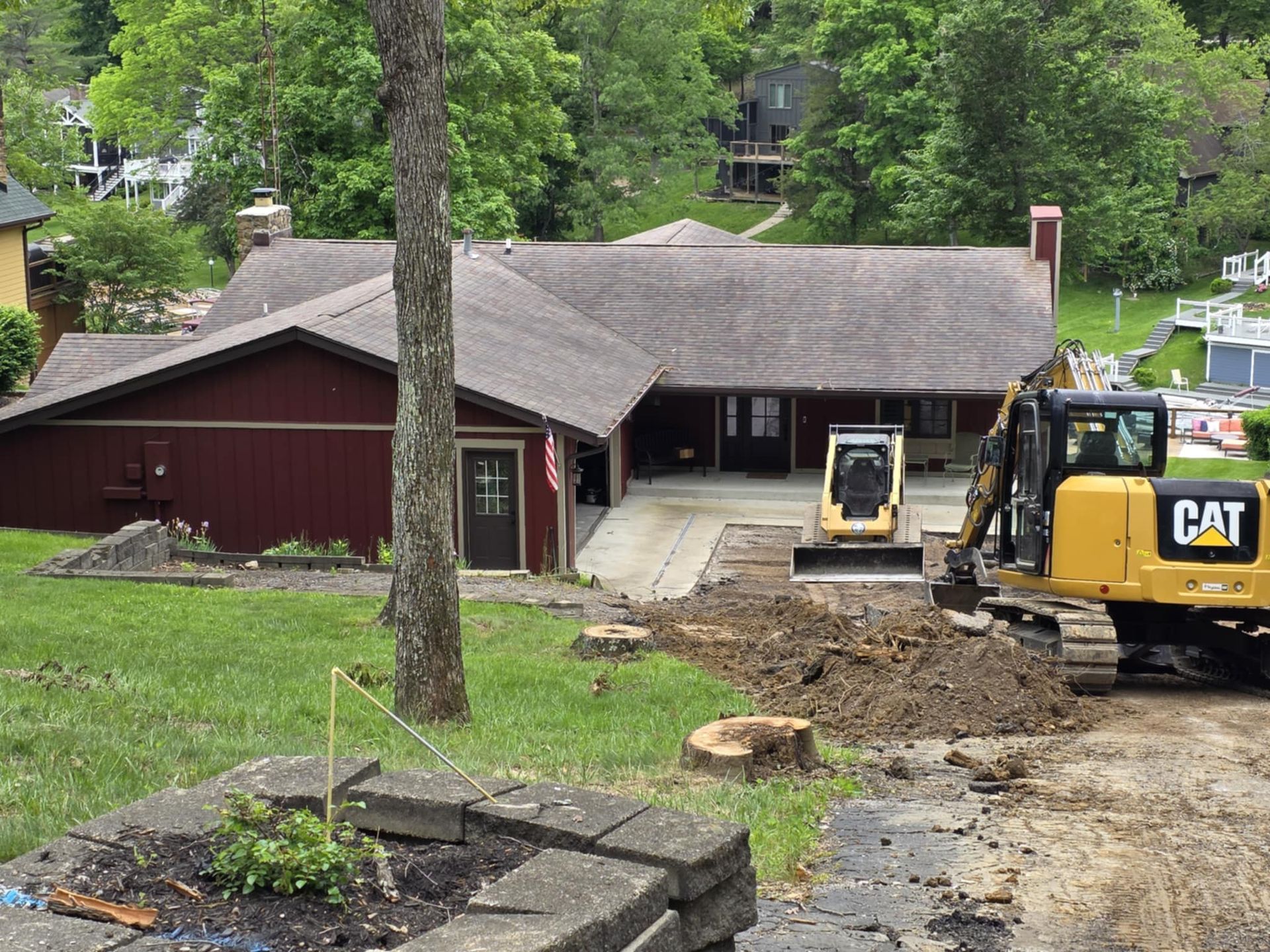 A cat excavator is working in front of a house