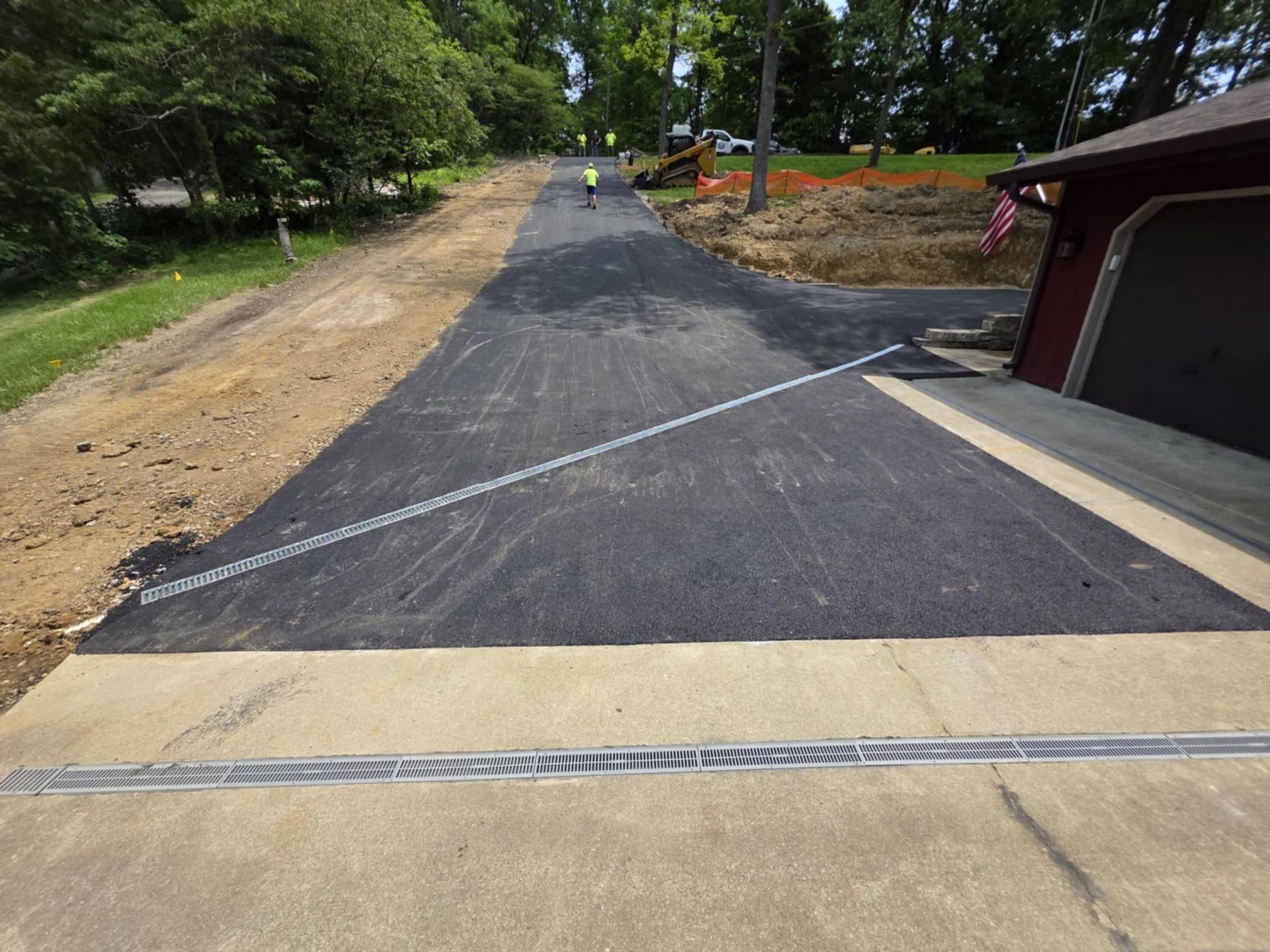 A newly paved driveway is being built next to a garage.