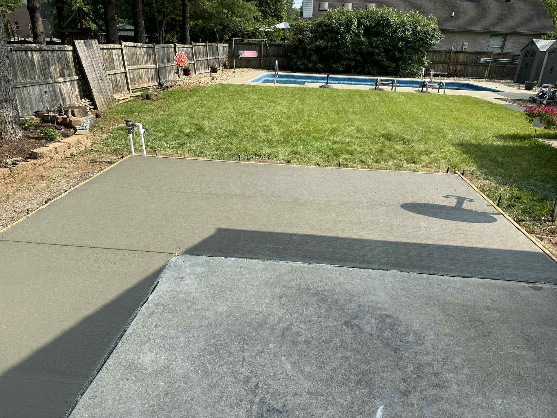 A concrete driveway leading to a swimming pool in a backyard.