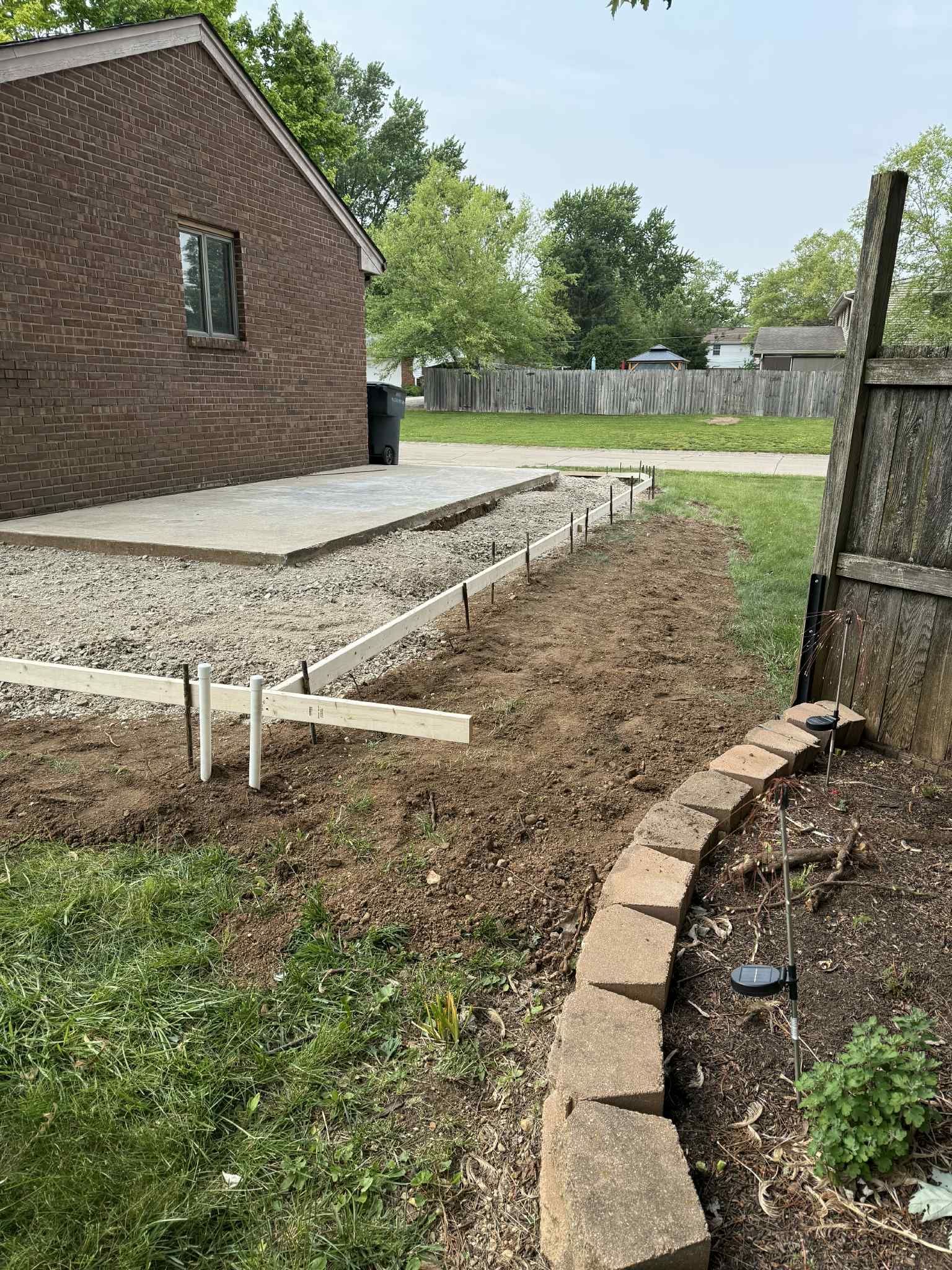 There is a brick house in the background and a fence in the foreground.