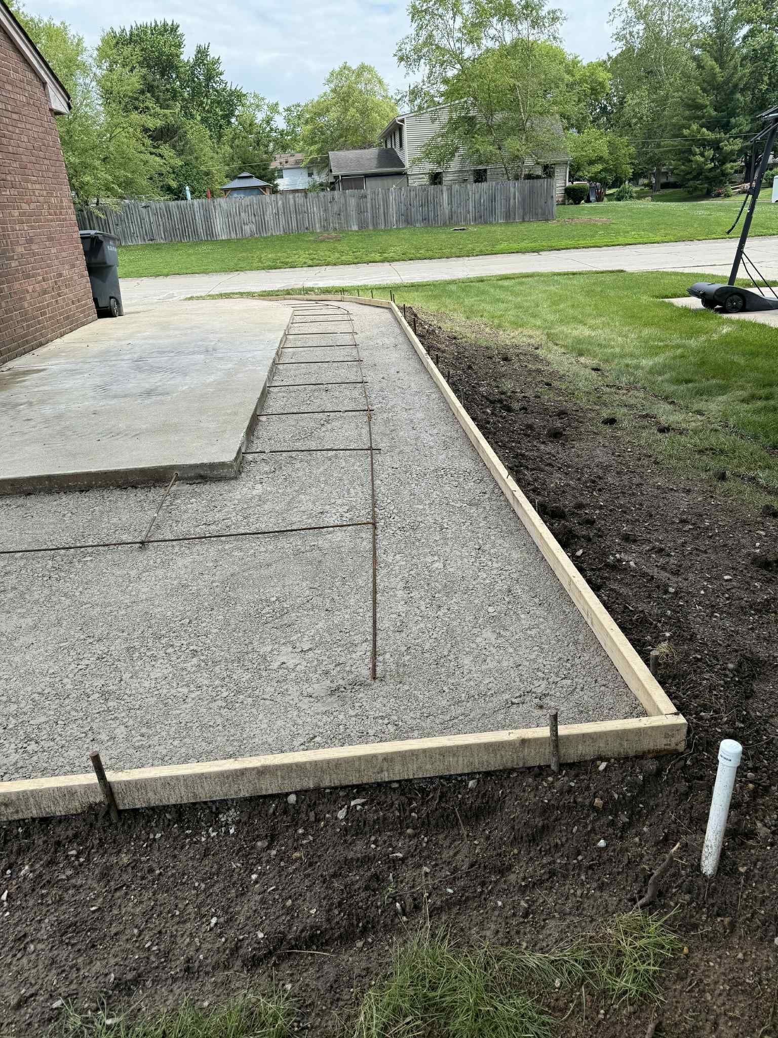 A concrete driveway is being built in the backyard of a house.