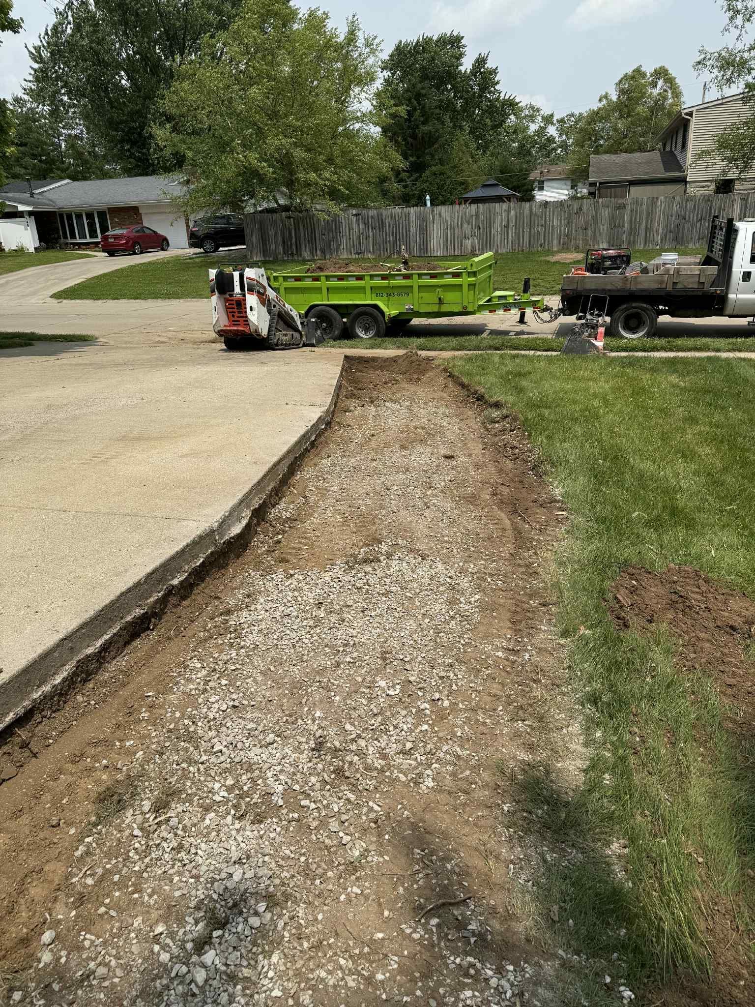 A dump truck is parked on the side of a gravel road.