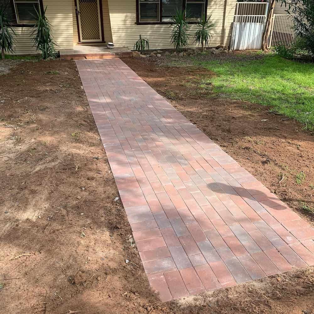 A Brick Walkway Is Being Built in Front of A House — Creative Spaces Landscaping in Dubbo, NSW