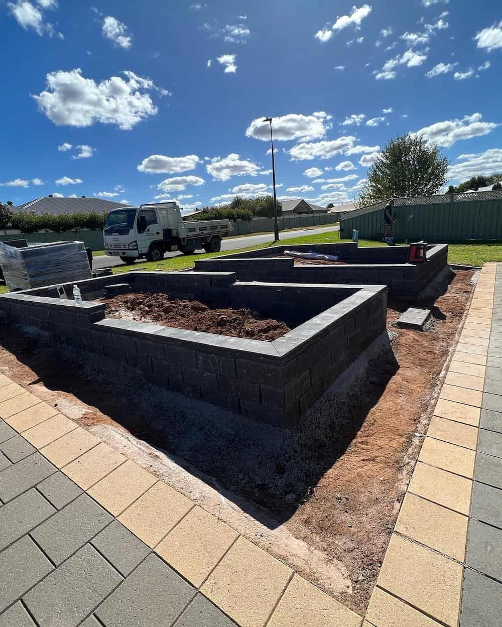 A Brick Retaining Wall Is Being Built in A Yard — Creative Spaces Landscaping in Dubbo, NSW