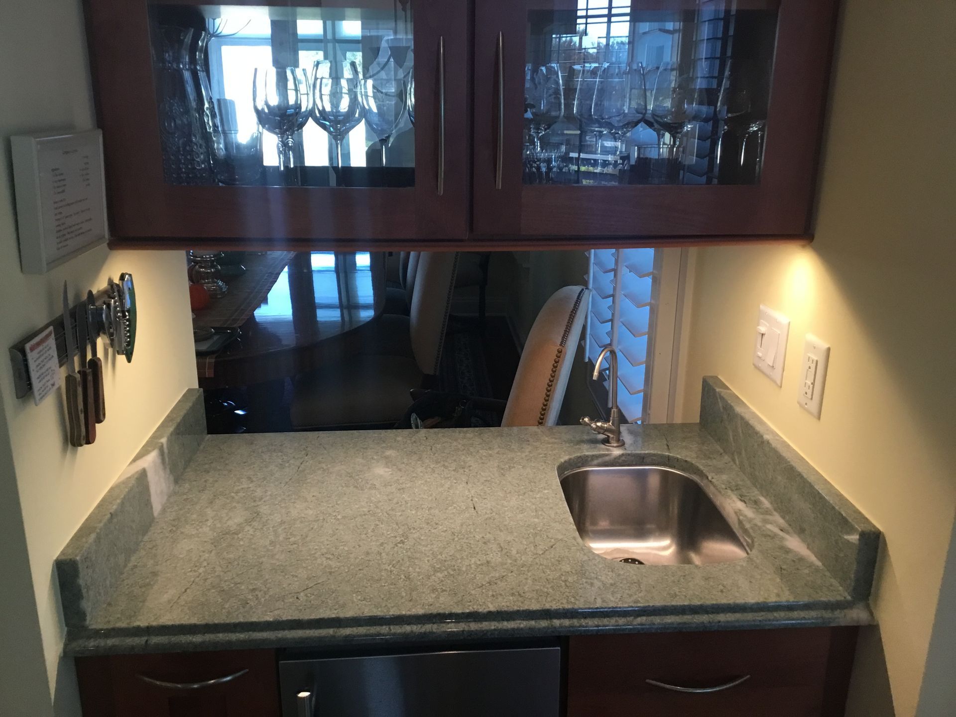 Wet bar with cabinets, countertop, sink, and under-cabinet lighting.
