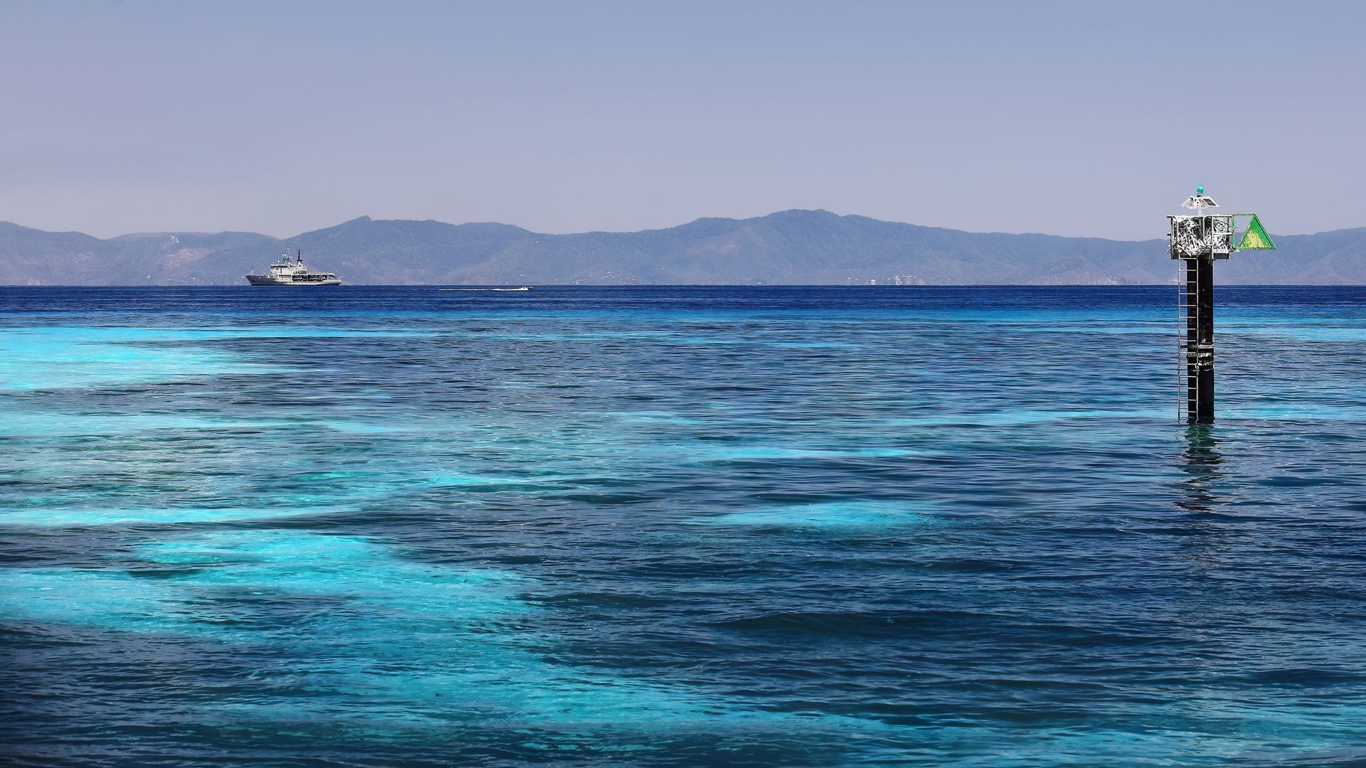 Ocean Scene With a Buoy, Distant Ship, and Mountains Under a Blue Sky — FNQ Cleaning Services in Trinity Beach, QLD
