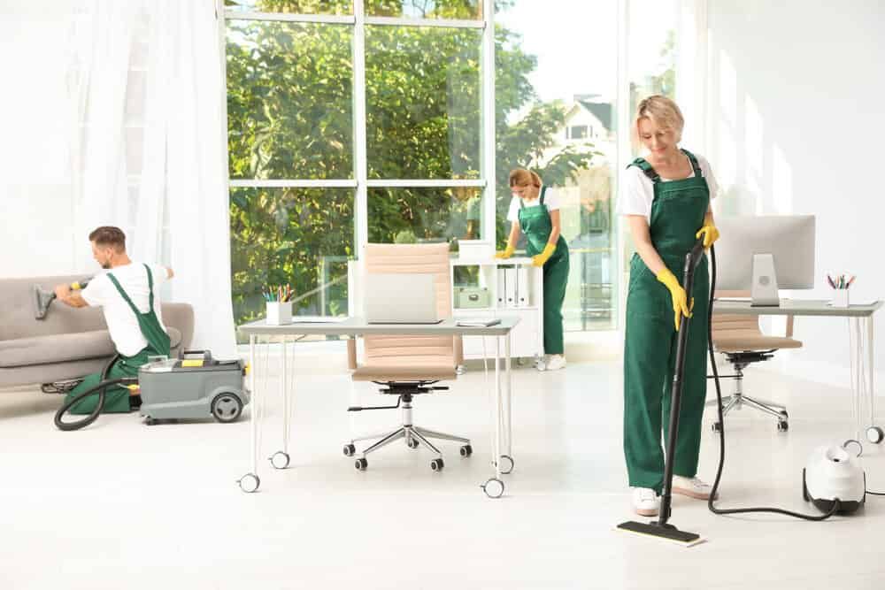 A Group Of Janitors Are Cleaning An Office — FNQ Professional Cleaning Services In Mooroobool, QLD