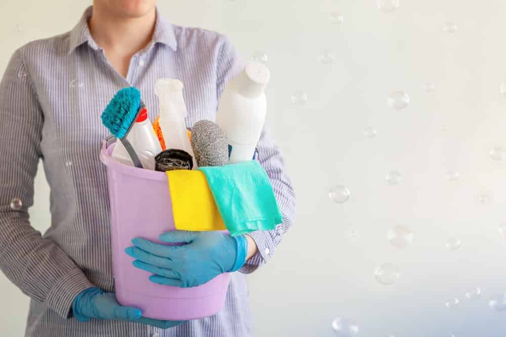 A Woman Is Holding A Bucket Full Of Cleaning Supplies — FNQ Professional Cleaning Services In Mooroobool, QLD