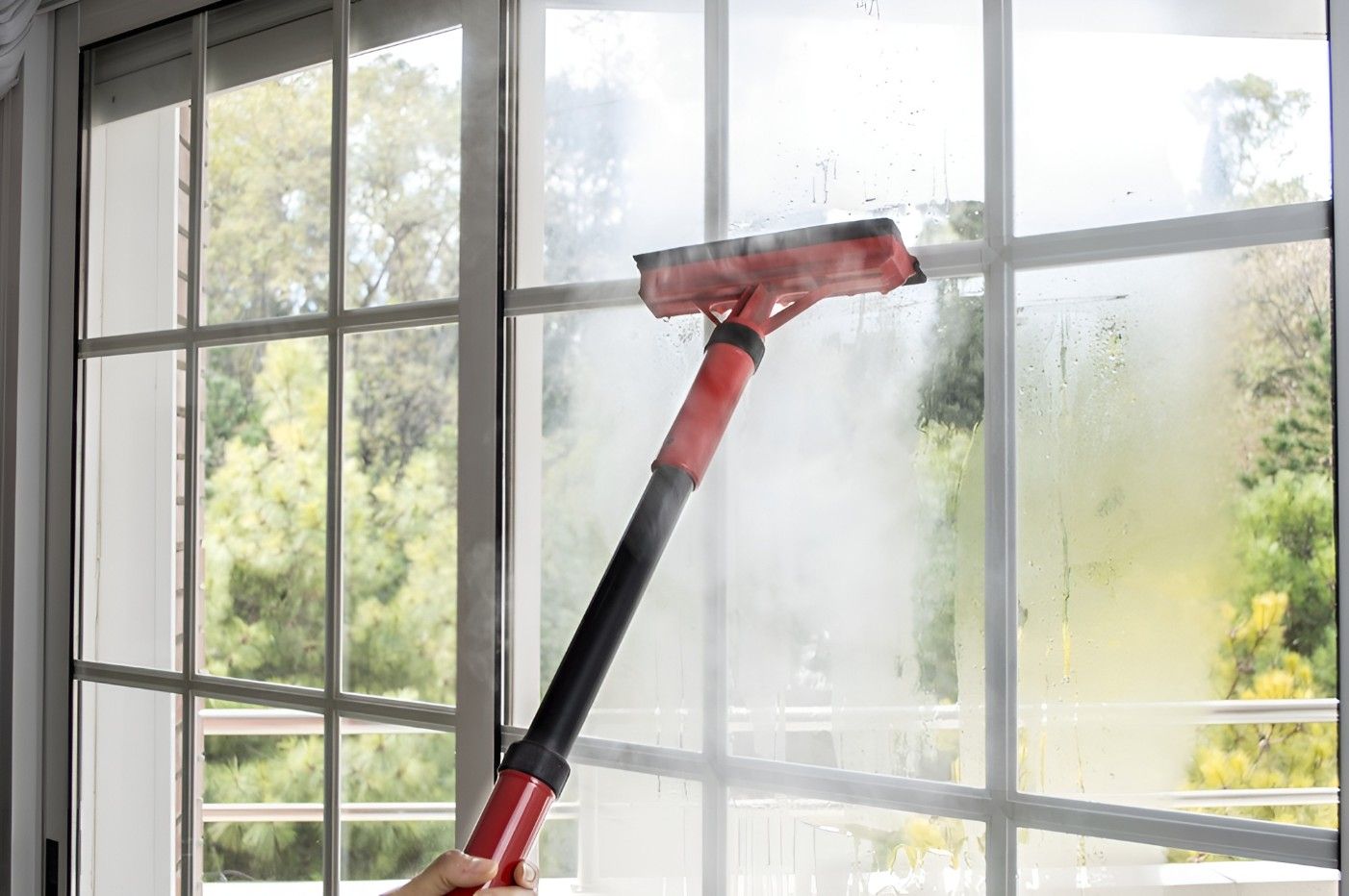 A Person is Cleaning a Window With a Steam Cleaner — FNQ Professional Cleaning Services In Mooroobool, QLD