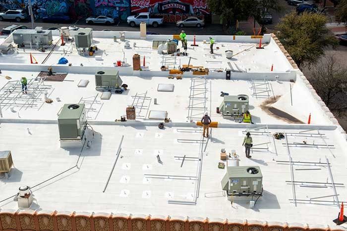 A group of people are working on the roof of a building.