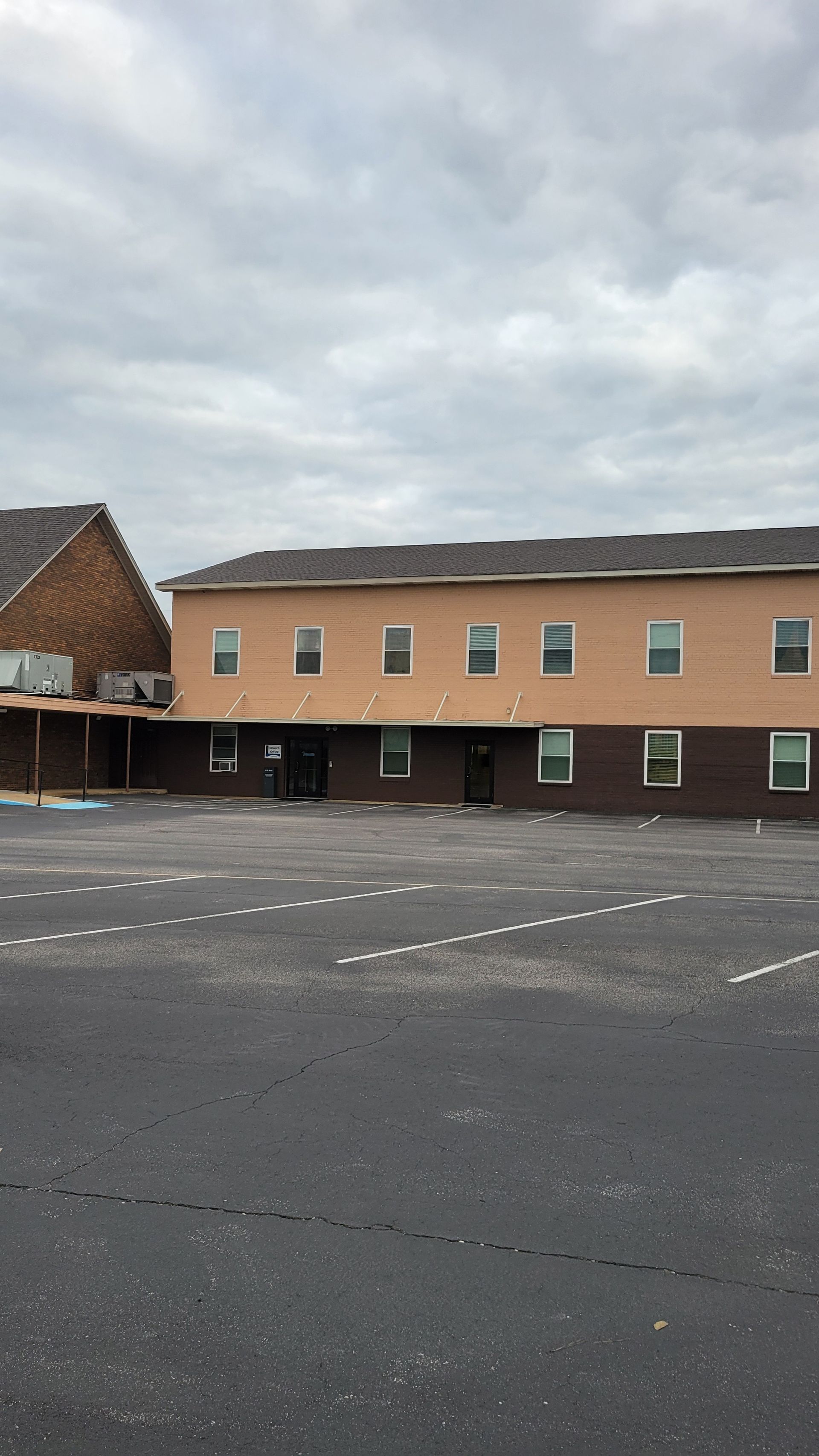 A large building with a lot of windows and a parking lot in front of it.