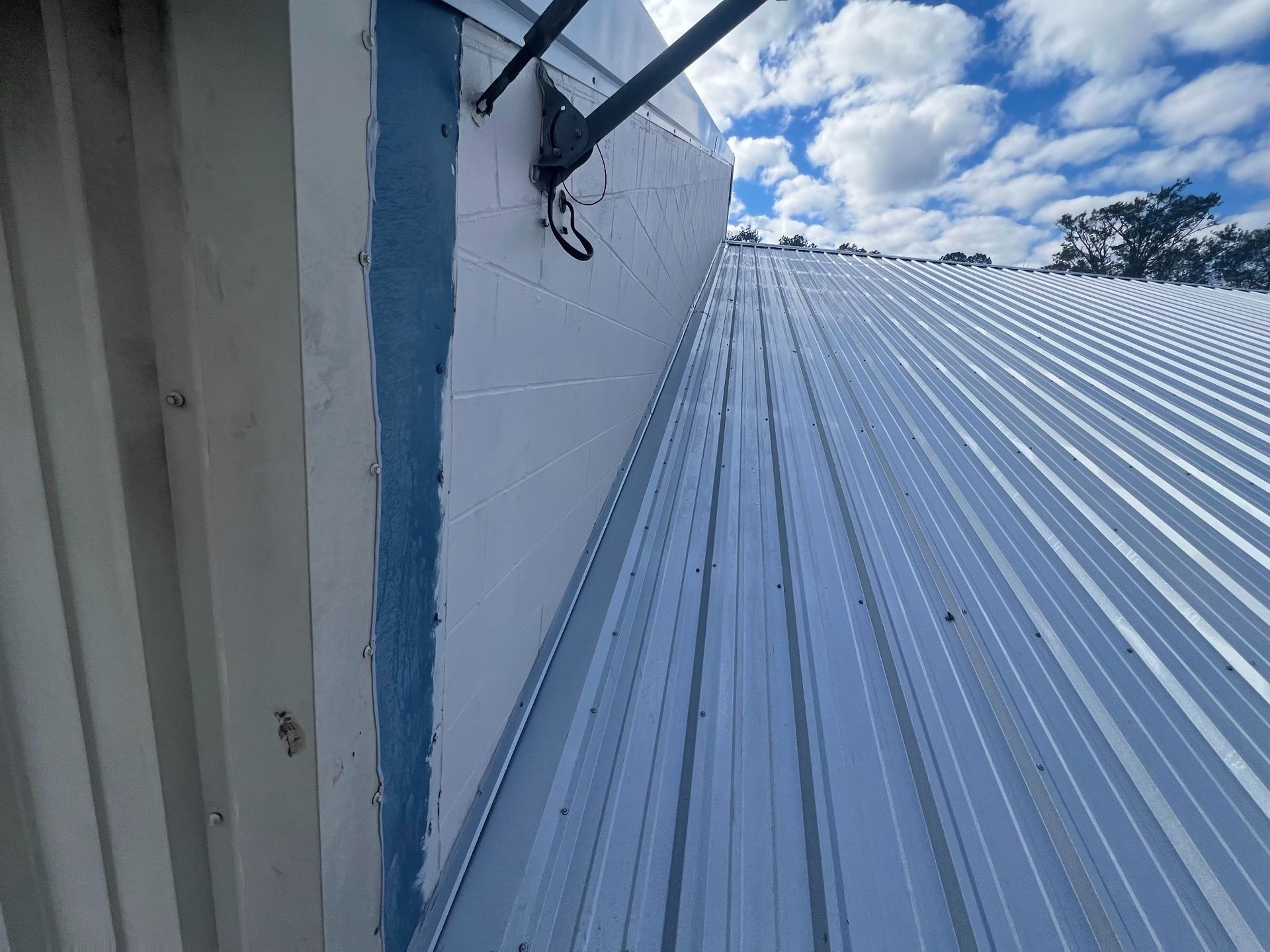A white building with a metal roof and a blue stripe on the side.