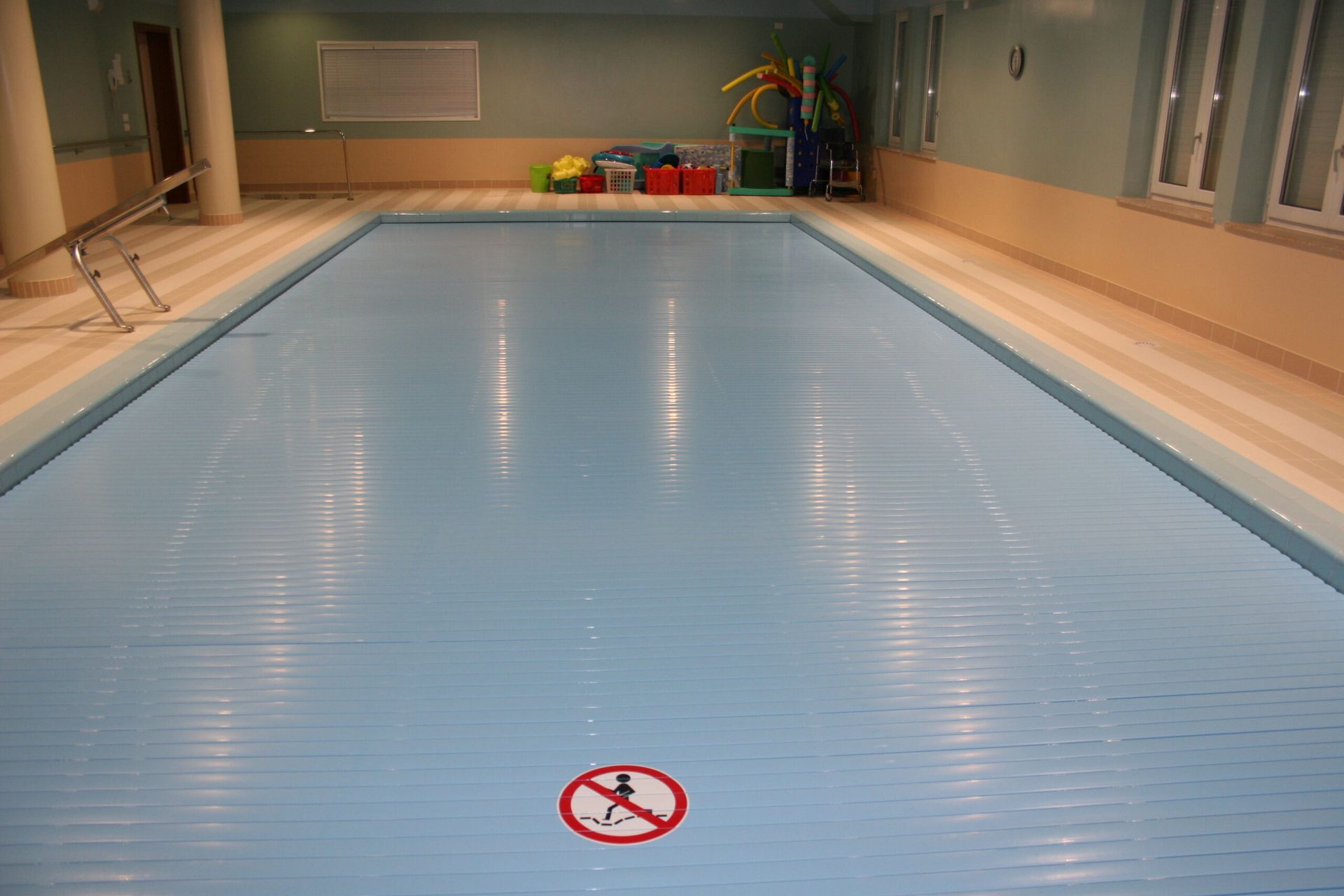 Piscina coperta con copertura blu chiusa; cartello 