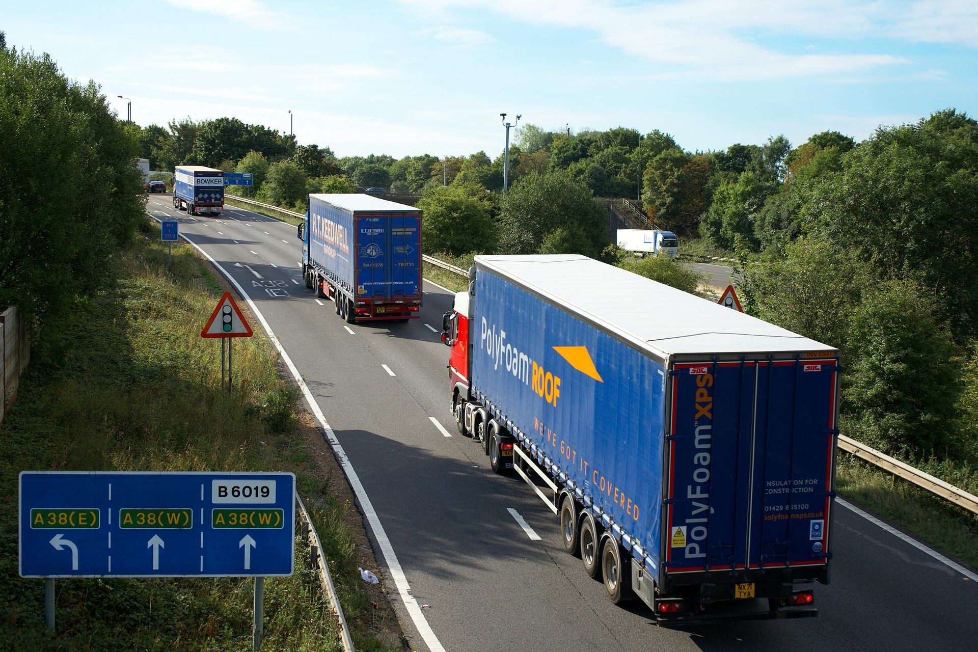 Several trucks are driving down a highway with a sign that says 6-90n