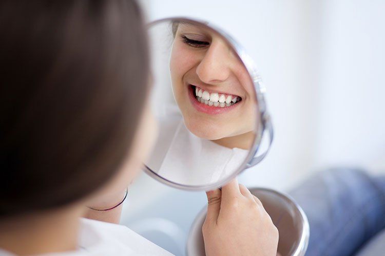 woman smiling into mirror