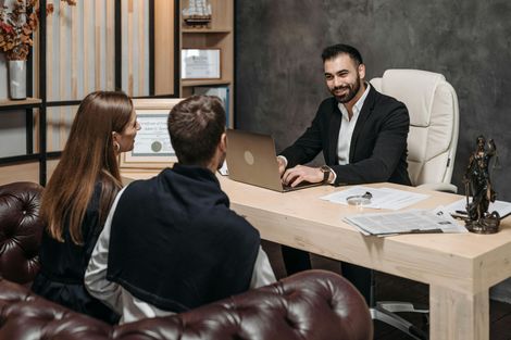 Couple consulting with a smiling professional at a desk in an office setting.