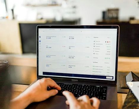 Person using a laptop with financial data displayed on the screen.